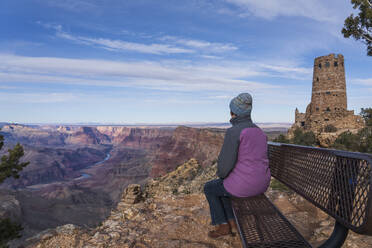 USA, Arizona, Rear view of female tourist sitting on bench in Grand Canyon National Park - TETF02075