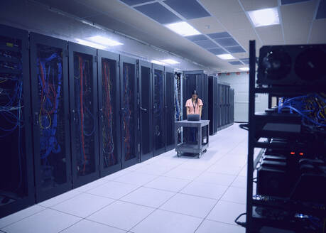 Female technician using laptop in server room - TETF02125