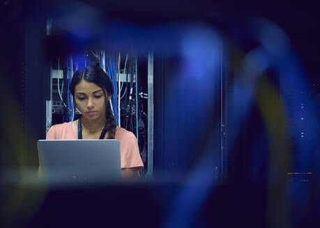 Female technician using laptop in server room - TETF02126