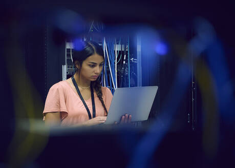 Female technician using laptop in server room - TETF02128