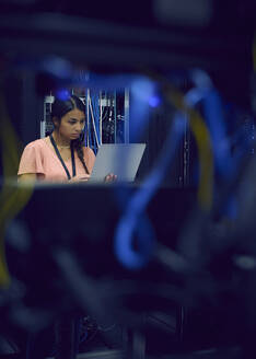 Female technician using laptop in server room - TETF02129