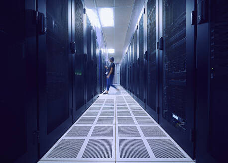 Female technician walking in server room - TETF02144