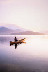 United States, New York, Woman paddling canoe on Lake Placid at sunrise, Adirondacks State Park - TETF02159