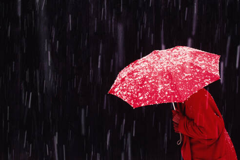 Woman walking in snowstorm with red umbrella - TETF02164