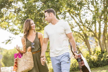 Woman and man holding hands and going for picnic in park - TETF02171