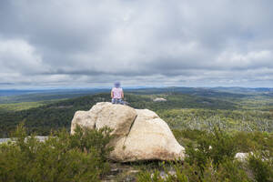 Australia, New South Wales, Bald Rock National Park, Woman sitting on rock and looking around - TETF02180