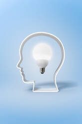 Glowing round bulb placed in white shaped human head isolated on blue background - ADSF44397