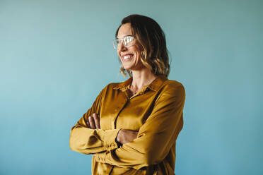 Confident business woman stands in a studio, wearing eyeglasses and smiling. Middle aged Caucasian woman representing success, professionalism and the spirit of entrepreneurship. - JLPPF02097