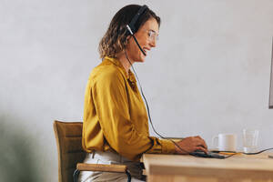Female call centre agent excelling in her role as a customer service consultant. With a headset and a smile, she expertly handles calls and ensures seamless communication in the contact center. - JLPPF02125