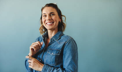 Woman representing the face of success as she stands in a professional studio. Dressed in business casual with a denim jacket, this happy and smiling entrepreneur is a true representation of a hardworking business person. - JLPPF02139