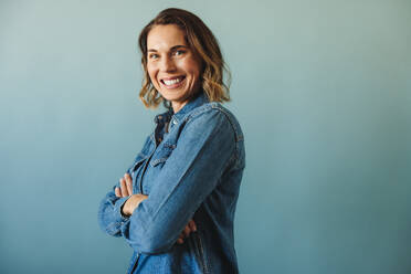 Portrait of a confident businesswoman, dressed in business casual attire, standing in a studio with crossed arms. Empowered female professional smiling at the camera confidently. - JLPPF02141