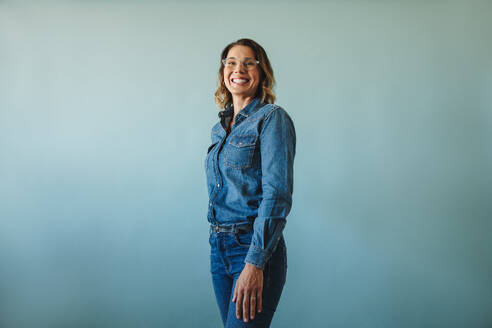 Female entrepreneur, wearing a denim outfit, presents a happy and engaging smile as she looks directly at the camera. Her professional demeanor and positive expression convey success and competence in her business endeavors. - JLPPF02144