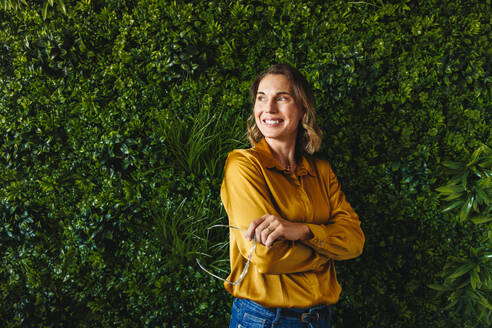 Caucasian female entrepreneur stands in an office with an eco-friendly design, reflecting her passion for sustainability. Businesswoman creatively thinking of ways to achieve a greener business model. - JLPPF02167