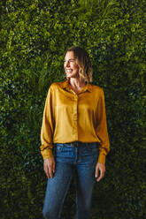 Happy and confident business woman proudly represents her sustainable company while standing in her eco-friendly office. Professional woman smiling as she stands up for workplace sustainability. - JLPPF02169