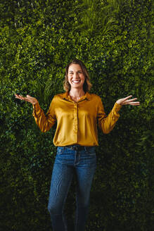 Female business owner celebrating her company's eco-friendly achievements. Businesswoman standing tall in a green office, smiling and reflecting her commitment to her company's success and sustainability. - JLPPF02170