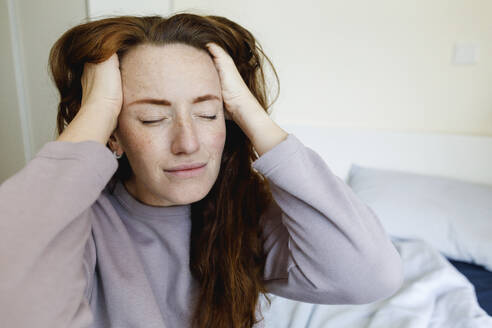 Woman with hands in hair sitting at home - TYF00798