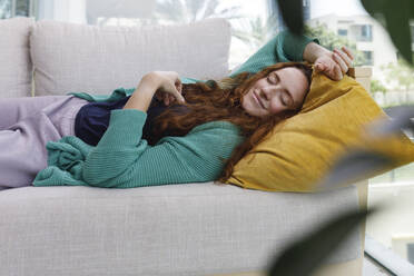 Lächelnde Frau schläft auf dem Sofa zu Hause - TYF00807