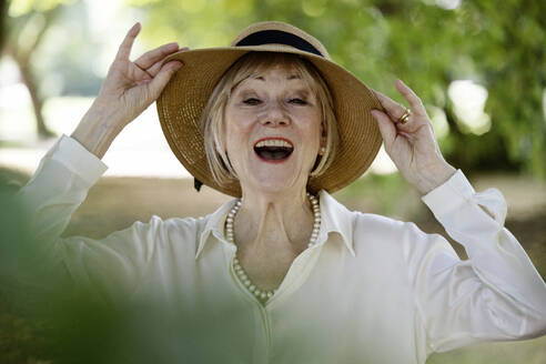 Cheerful woman wearing hat at park - JATF01371