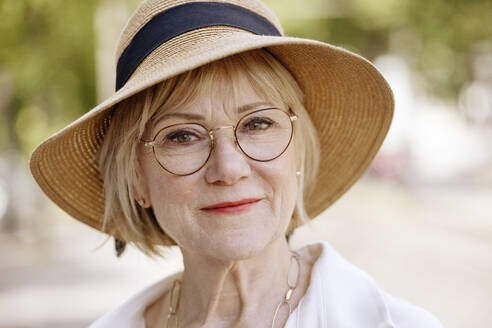 Senior woman wearing eyeglasses and hat at park - JATF01372