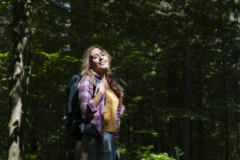 Hiker with eyes closed enjoying sunlight in forest - NDEF00884