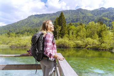 Backpacker with eyes closed enjoying in front of river and mountains - NDEF00887