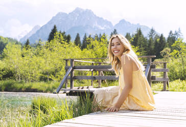 Lächelnde Frau sitzt und genießt die Aussicht im Naturschutzgebiet Zelenci - NDEF00908