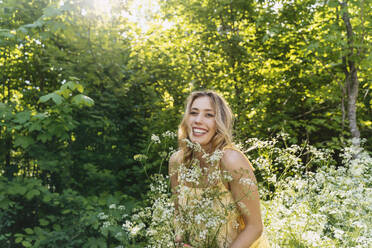 Beautiful woman standing amidst flowers in forest - NDEF00916