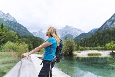 Hiker enjoying mountain view from pier over river - NDEF00932