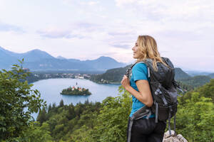 Lächelnder Wanderer genießt den Blick auf den Bleder See vor dem Himmel - NDEF00948