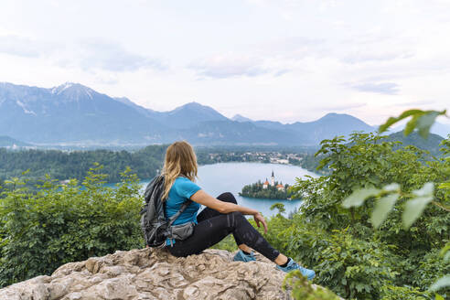 Wanderer mit Blick auf den Berg auf einer Klippe sitzend - NDEF00949