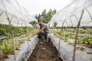 Junger Landwirt in Gummistiefeln bei der Arbeit auf dem Bauernhof - IKF00942