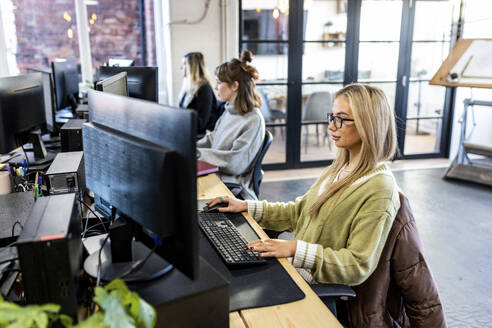 Junge Geschäftsfrauen bei der Arbeit an einem Desktop-PC im Büro - WPEF07421