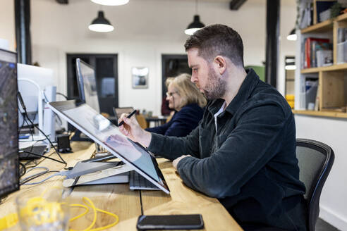 Architekt arbeitet an einem Grafiktablett am Schreibtisch - WPEF07463