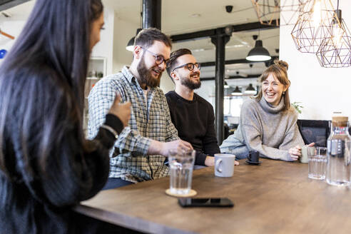 Glückliche Geschäftsleute, die eine Pause machen und miteinander im Büro reden - WPEF07499