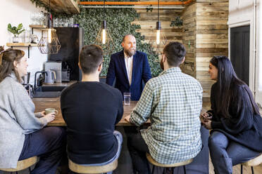 Mature businessman having discussion with colleagues in office cafeteria - WPEF07503