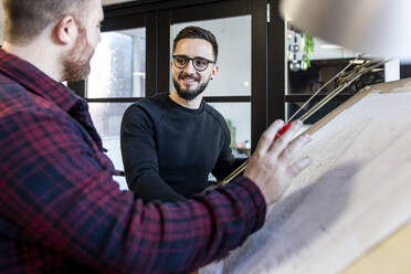 Glückliche Architekten bei der Arbeit an einem Bauplan im Büro - WPEF07507