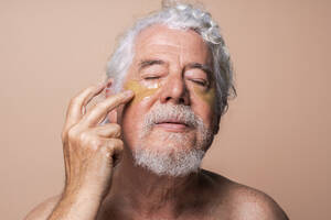 Älterer Mann mit geschlossenen Augen klebt Augenklappe auf - OIPF03151