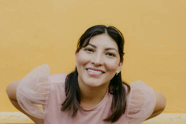 Happy woman in front of yellow wall - DSIF00676