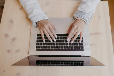 Hände einer Frau beim Tippen auf einem Laptop am Schreibtisch - DSIF00678