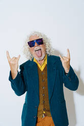 Cheerful senior man sticking out tongue and gesturing against white background - OIPF03161