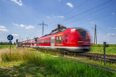 Deutschland, Nordrhein-Westfalen, Beckrath, Unscharfe Bewegung eines roten Personenzugs - FRF01025