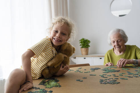 Großmutter löst ein Puzzle und Enkelin hält Teddybär - SVKF01484