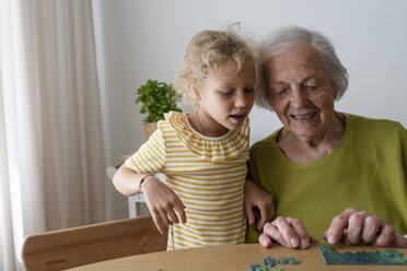 Großmutter bringt ihrer Enkelin bei, wie man ein Puzzle zu Hause löst - SVKF01489