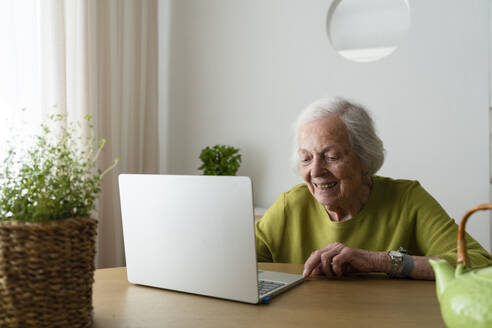 Senior woman using laptop on table at home - SVKF01505
