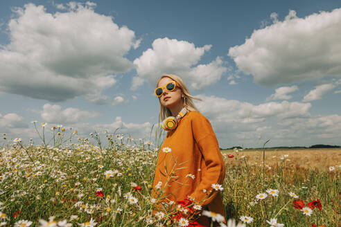 Blond woman standing in chamomile field - VSNF01112