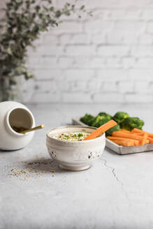 Bowl of feta-honey dip and raw carrots and broccoli - SBDF04640