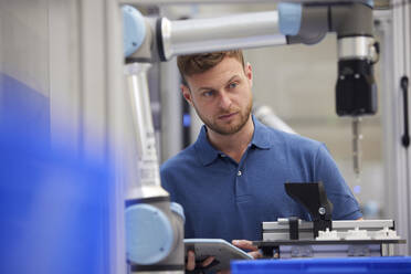 Focused engineer examining robotic machine in industry - RBF09033
