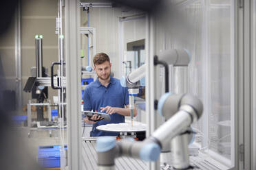 Technician examining modern robotic machine in industry - RBF09037