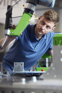 Focused engineer analyzing machine part in modern factory - RBF09048