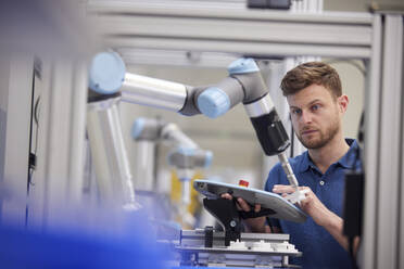 Engineer testing robotic arm using equipment in industry - RBF09052